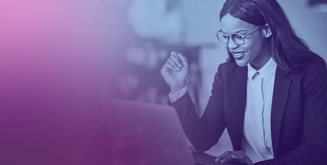 Happy woman in a black blazer working on her laptop.